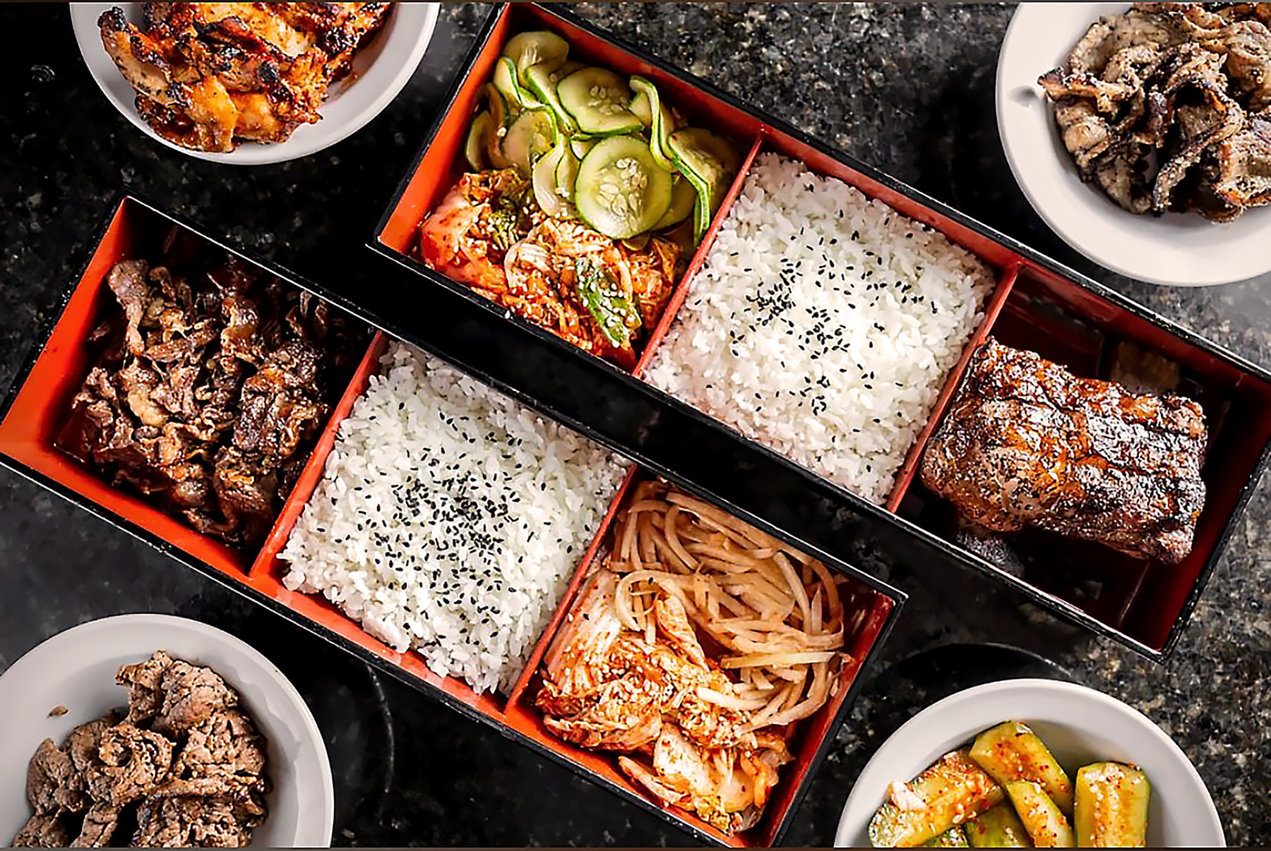 korean barbeque with rice and sides in bento boxes